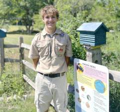 Boy Scout Mattias Eriksson stands next to one of his mason bee homes.