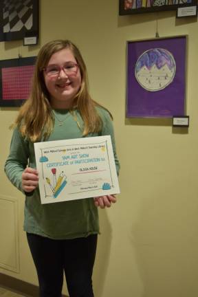 Olivia House of Apshawa Elementary School with her certificate of participation and artwork.