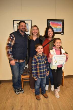 Ella Brannan, holding her certificate of participation, poses with her family.