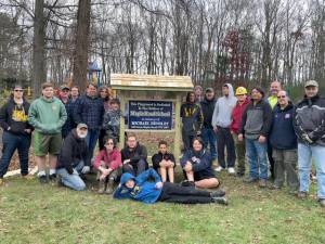 Members of Scouts BSA Troop 159 and Venturing Crew 1204 pose by the rebuilt wishing well at Maple Road Elementary School.