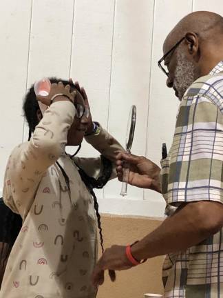 Campers given free glasses Optician Floyd Patterson of Vauxhall holds up a mirror for Haile Thomas to see herself wearing new glasses.