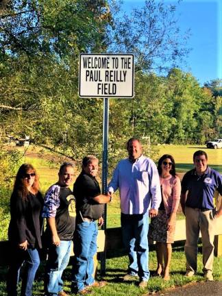 Township Council president Peter McGuiness, right center, congratulates Paul Reilly after the opening of a field in his name Wednesday night.