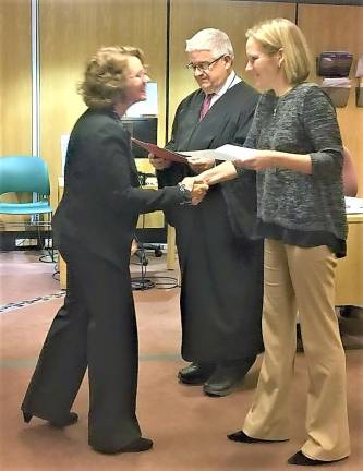 Jennifer McIntyre (Left) shakes hands with CASA Executive Director Erica-Fischer Kaslander (right) as she receives her certificate.