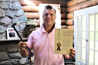 Charles Bocar, holding his invention and patent for The Ape Scraper at his West Milford home.