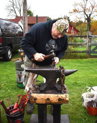 Blacksmith Bill Barrett hammers a billet into a wall hook during a demonstration Sunday, Oct. 22 at the Wallisch Homestead in West Milford. (Photo by Fred Ashplant)