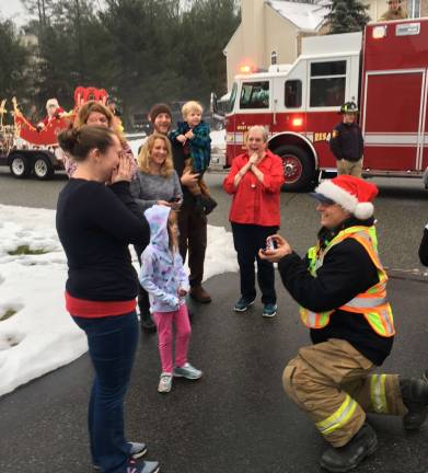 Photo provided by Mike DelVecchio Mike Miller gets down on one knee proposing to his girlfriend, Jillian Albrecht, during Fire Company 4's Santa ride last Sunday, Santa is watching, at left, and Albrecht's mom, Andrea, in red, is thrilled.