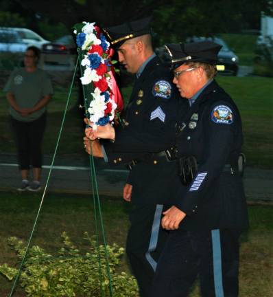 [Police officers lay a wreath at the 9/11 memorial in front of Town Hall Wednesday night. Charles Kim photo]