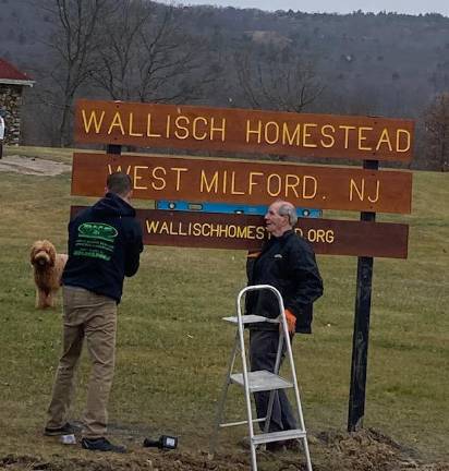 Mark Lynch and Collin Murphy install the new Wallisch Homestead at the 65 Lincoln Ave entrance.