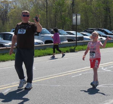 This dad and daughter gave a wave as they approached the finish line.