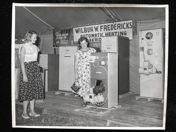 Looking back: Mayor Fredericks and the fair Visitors look at home heating products displayed by Mayor Wilbur Fredericks at the Community Fire Company of Newfoundland and Oak Ridge Country Fair, which ran annually from 1950 to 1994. (File photo by Ann Genader)