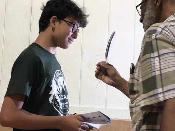 Campers given free glasses Optician Floyd Patterson holds up a mirror for Maxim Reyes to see his new glasses.