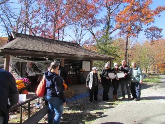 YMCA of Montclair representatives show framed citations presented by the West Milford Economic Development Committee (EDC) outside the current YMCA headquarter building at the 30-acre property camp site in West Milford. EDC Chair Joann Blom is at left with Ann Margaret Gutiervez, Chief Operating Officer for the YMCA next to her. Councilwoman Ada Erik is at right.