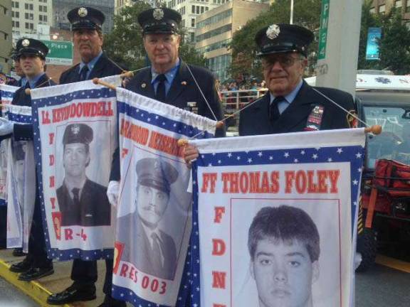 New Jersey Firefighter John Monteleone, right, holds a banner depicting fallen firefighter Thomas Foley, during the recent Tunnels to Towers 5K Run &amp; Walk. Photo provided