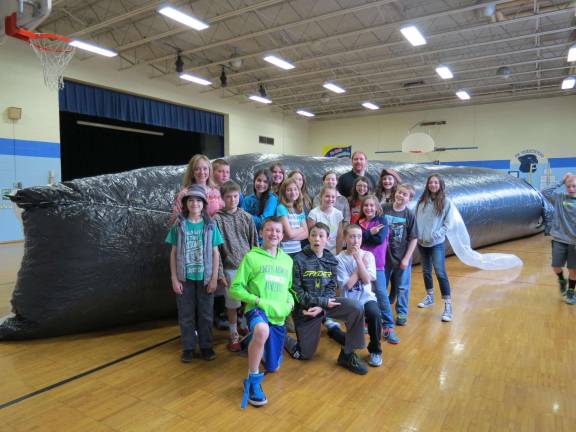 Sixth grade students from Shannon Ricker's class pose in front of Henry the Humback Whale to demonstrate the size of the creature creation.