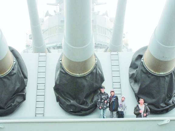 Cub Scouts from Pack 51 pose for a picture by the massive front gun turrets of the Battleship New Jersey.