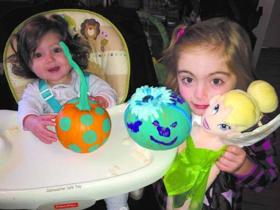 Four-year-old Samantha, with her good friend Tinkerbell, and her little sister Violet show off their teal pumpkins for the Teal Pumpkin Project. Violet had some help decorating hers!
