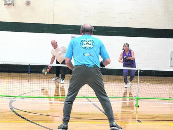 Rich Lenihan returns the pickleball to Jim Zajdel. At right is Lorette Lenihan. (Photo by Kathy Shwiff)