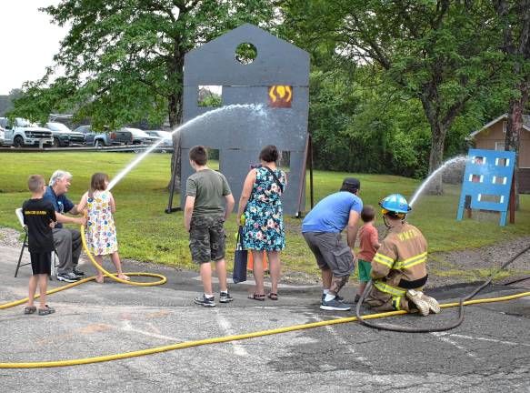 Community gathers for National Night Out Children use fire hoses to ‘put out the house fire.’