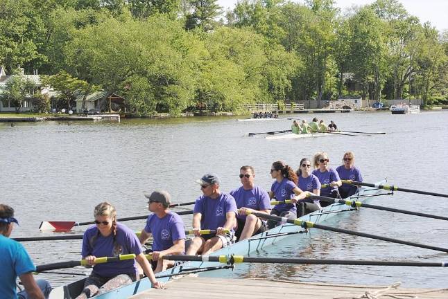 The Green Team Realty Mixed Crew, coached by Jim Cody, waits at the dock as the Aspire Financial Coaching crew, coxed by Steve Schermerhorn, sprints for the finish line.