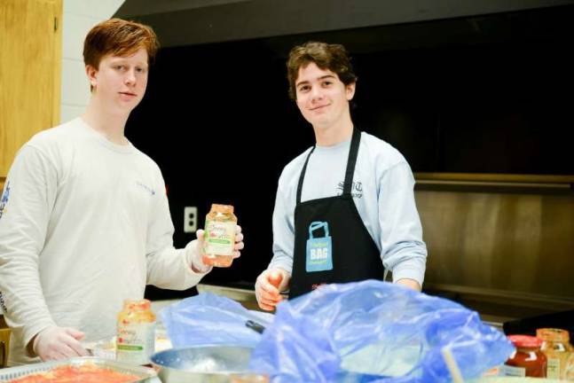 Youth ministry provides meals and more for families in need John Gaffney and Aidan Kelly of St. Joseph's Church's Youth Ministry work on lasagna at the Apshawa Firehouse.