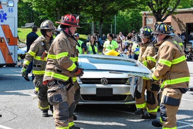 Simulated crash meant as warning Firefighters remove the hood of a car.