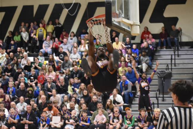 A member of the Wizards team hangs from a basket in the West Milford High School gym.