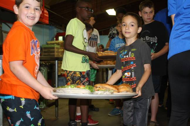 The Summer of a lifetime Campers carry their freshly-made lunch back to their table.