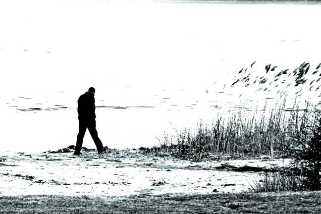 Though a brisk wind and lingering showers were less than inviting, a lone man walks along the shore at the beach at Wawayanda State Park on Easter Sunday afternoon.