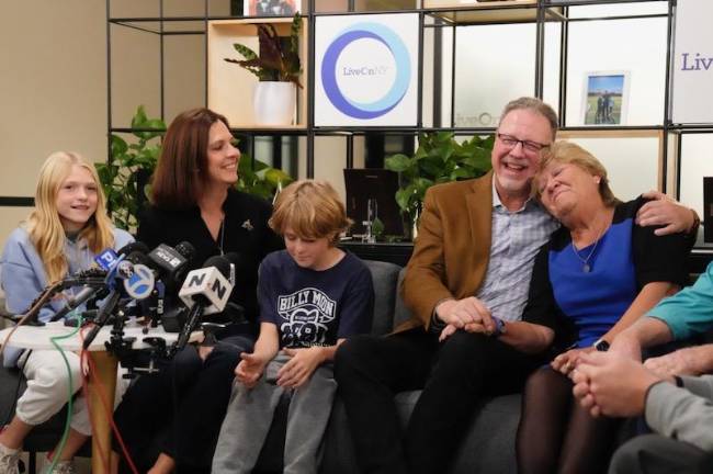 Rich Grehl hugs Patty Moon, mother of Billy Moon, a New York City firefighter who died last December. Grehl received his heart in a transplant. At left are Moon’s daughter, Brianne, 11; widow, Kristina; and son, Colin, 9.