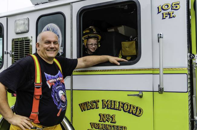 Sweet ALF Firefighter Krzysztof Czus giving future Firefighter Jeo Ziemba a tour of the passenger seating in the rear of West Milford Co. 1 areal ladder.