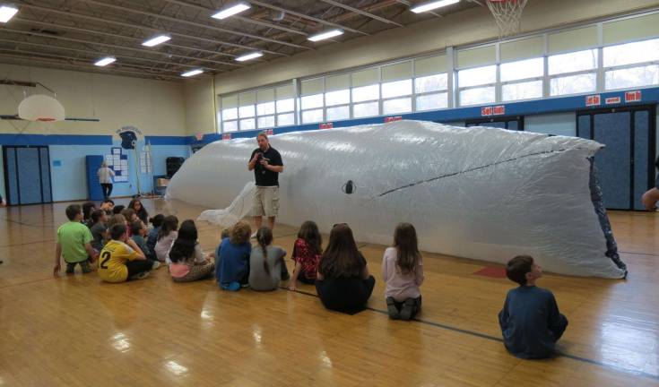 Third grade students listen attentively as Keith Bradley teaches them some facts about humpback whales.