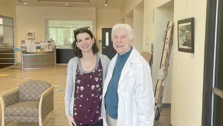 Interim Library Director Sara Cassaro stands with Carolyn Ott, who donated the piano in her husband’s name.