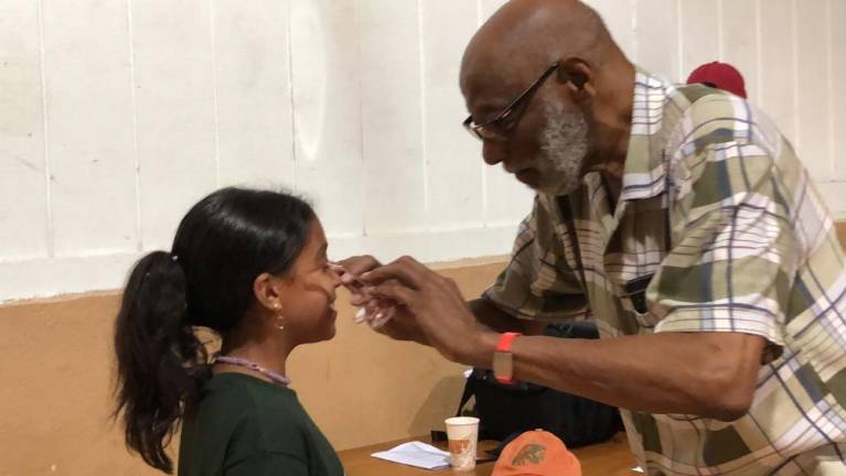Campers given free glasses Optician Floyd Patterson helps fit new glasses on Jasayra Gonzalez.