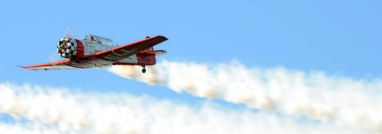 A vintage plane blows smoke just to show off. For those who know, the skill of the pilot is what counts, not the smoke. But you knew that.