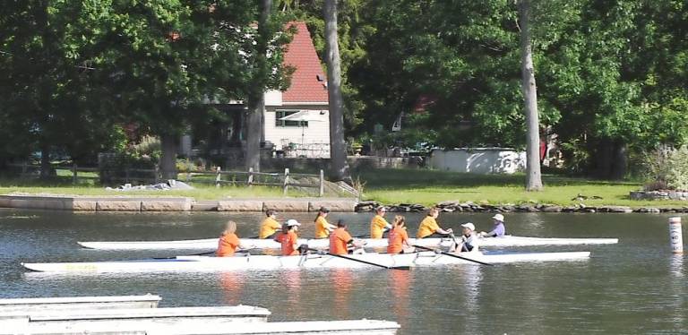 The Warwickinfo.net crew, coxed by Donna Van Tiegham, heads to the starting line alongside the UN Sustainable Development Goals crew, which was coxed by founding member Stan Goodman.