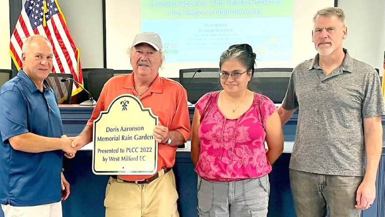 West Milford Environmental Commission Chairman Steve Sangle presents Pinecliff Lake Community Club representatives with a sign to be placed at the Doris Aaronson Memorial Rain Garden being constructed at the lake community clubhouse. From left to right are Ed Spirko, West Milford Environmental Commission Chair Steve Sangle, Roxanna Saltos-Banks, and Don Weise. Spirko and Saltos-Banks represent the community club. Weise is a commissioner with the Environmental Commission and is with the NY/NJ Trails Conference.