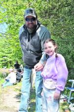 Youngster Jordyn, with dad, after catching a fish, said, “I like the grey ones best. I fish in my backyard where I catch lots of fish. And I always take the hook off myself.”