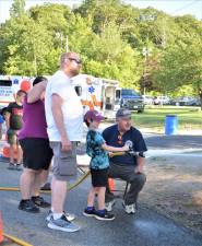 A boy directs a fire hose during the National Night Out celebration Tuesday, Aug. 1 at West Milford High School. (Photo by Fred Ashplant)