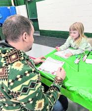 Juniper Savage Foley, 4, of West Milford writes her letter to Santa as her father, Jim Foley, looks on.