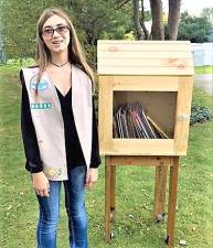 Girl Scout Olivia Schmelz stands next to one of the free lending libraries she built to help her earn the Silver Award.