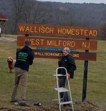 Mark Lynch and Collin Murphy install the new Wallisch Homestead at the 65 Lincoln Ave entrance.