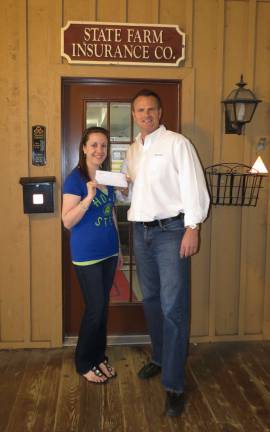 Lyndsay Wright accepts a check for $1,000 from Tom Ziegenbalg, owner of the Ziegenbalg Agency in West Milford. The businessman hosted a shredding event, free to the community, and asked for donations for the MS Society.