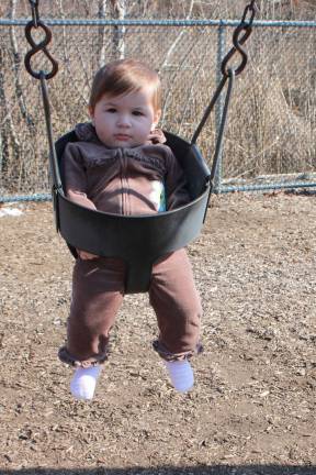 Welcoming the spring-like weather on Sunday afternoon, seven-month old Sofia Berardi seems to be givng this swining thing a good deal of thought. Forward and back, her expression never changed. Hopefully, she'll soon decide that playgrounds are fun indeed. Photo by Ginny Raue