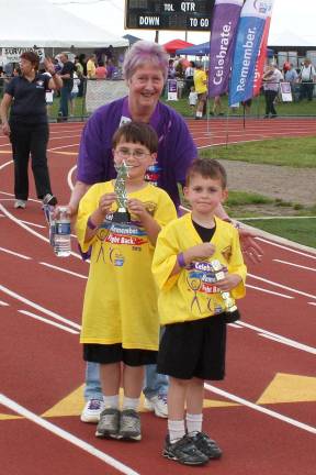 Joan Hopper, director of communications for the Relay, and Matthew and Tyler Evans, two youngsters who worked along withe their mom, Vickie Evans, co-chairperson of the event. The boys were awarded special trophies for their efforts on behalf of the Relay. Photo by Ginny Raue