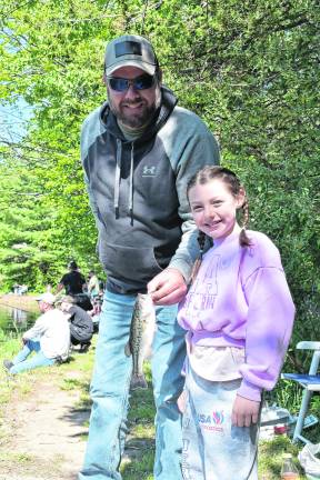 Youngster Jordyn, with dad, after catching a fish, said, “I like the grey ones best. I fish in my backyard where I catch lots of fish. And I always take the hook off myself.”