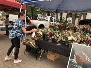 Tiffany Reamer of Floral Ideology in Wayne sprays the flowers to keep them fresh on opening day of the West Milford Farmer’s Market on Wednesday, June 7. (Photo by Kathy Shwiff)