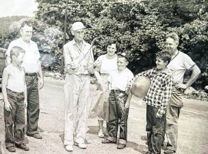 Water dowser “Charlie” Decker demonstrates how he finds a place where a well water supply could be abundant. Seen in a 1950s photo from left are: Peter Gillen Jr., Peter Gillen Sr., Charles Decker, Anna Romlein Struble, Parrick Gillen, Corky Struble, Floyd Struble Sr.