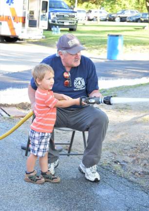 A boy helps direct the fire hose.