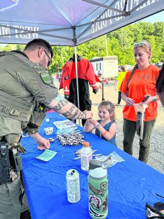 Kenzie Verbeke, 4, of Stockholm gets a vehicle-shaped keychain from Det. Derek Finley while Rita Vander Stad watches.