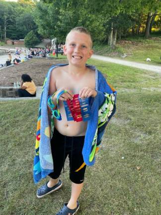 A swim team member holds his ribbons.